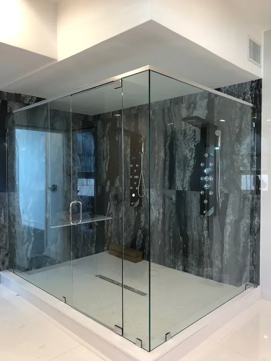 Remodeled bathroom with a frameless glass walk-in shower and dark marble-look tile walls